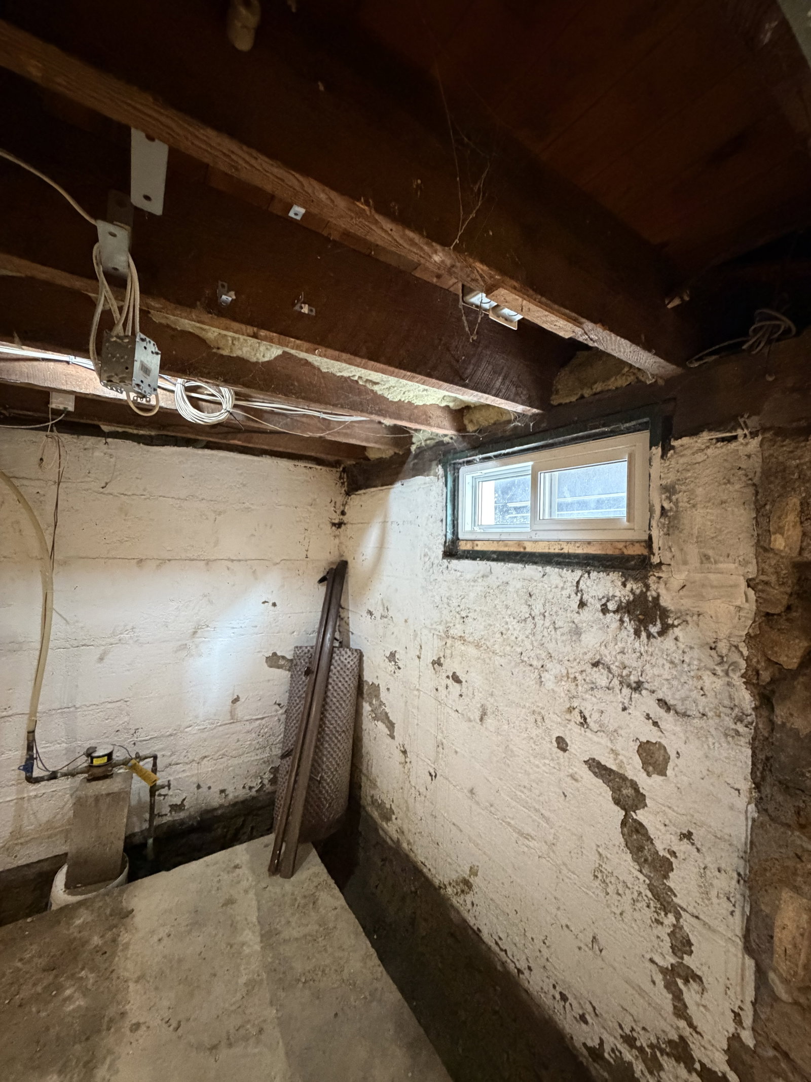 Dilapidated basement with exposed beams.