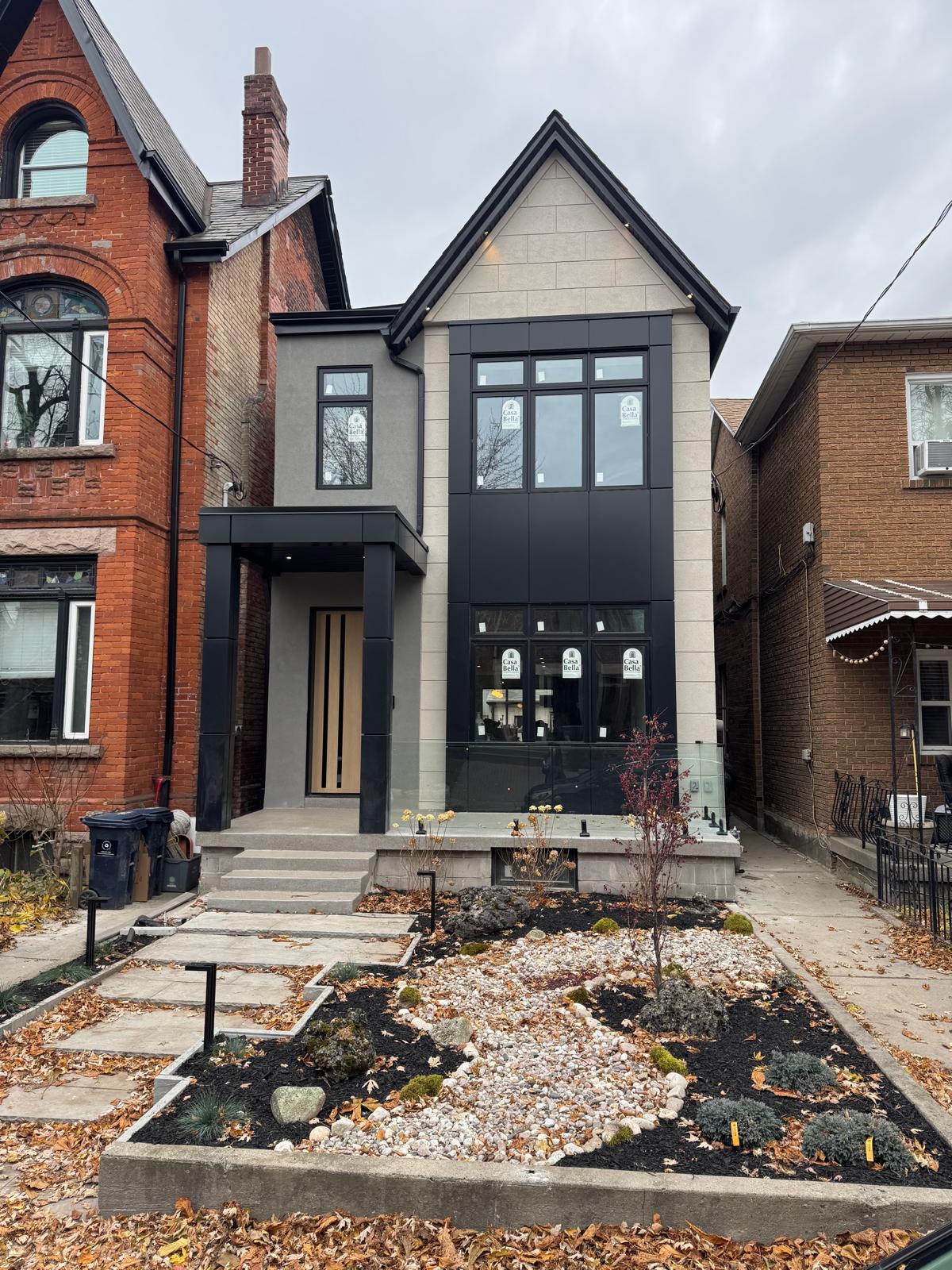 Side view of a modern home addition with dark siding and brick integration.