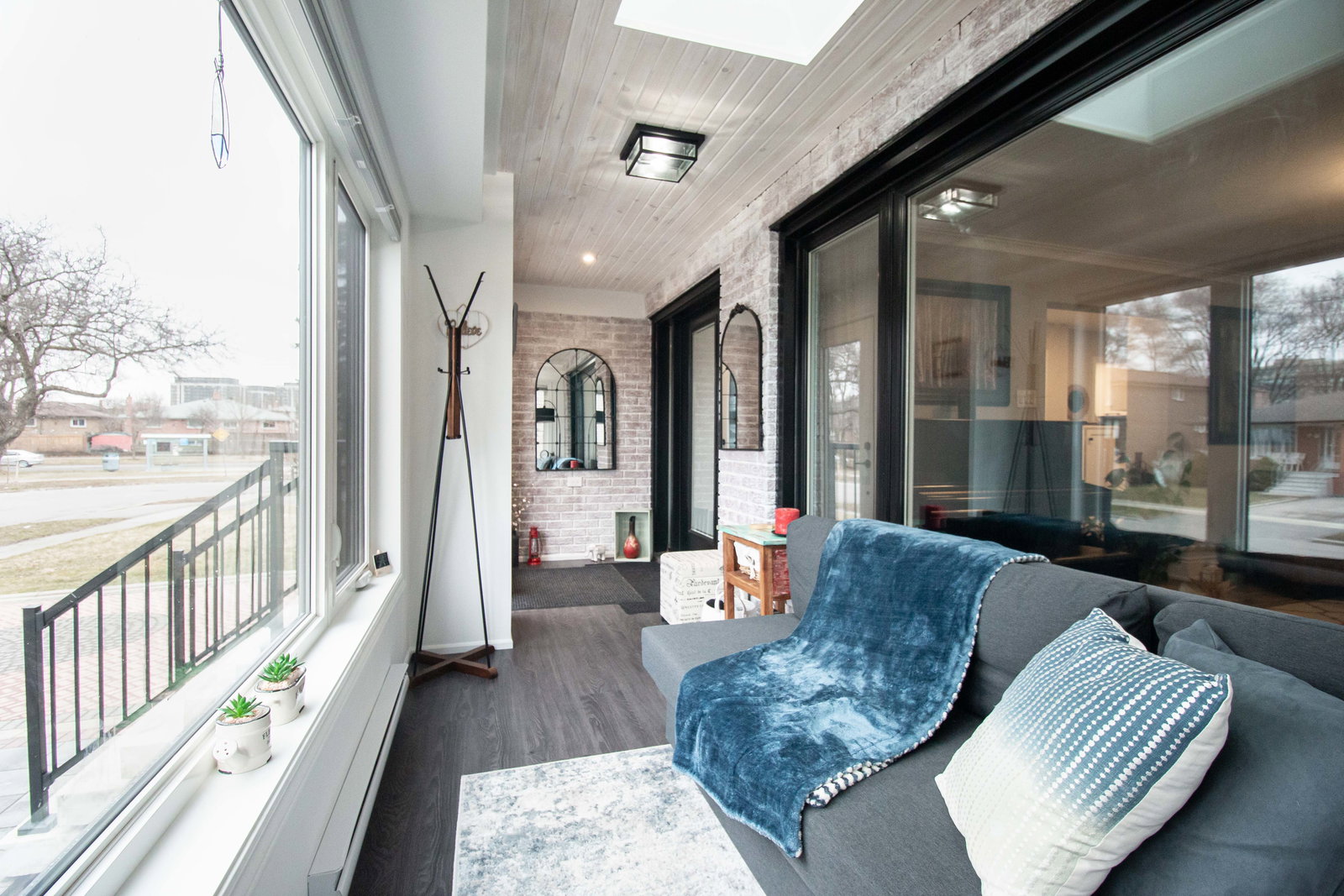Bright sunroom addition with a grey sofa.