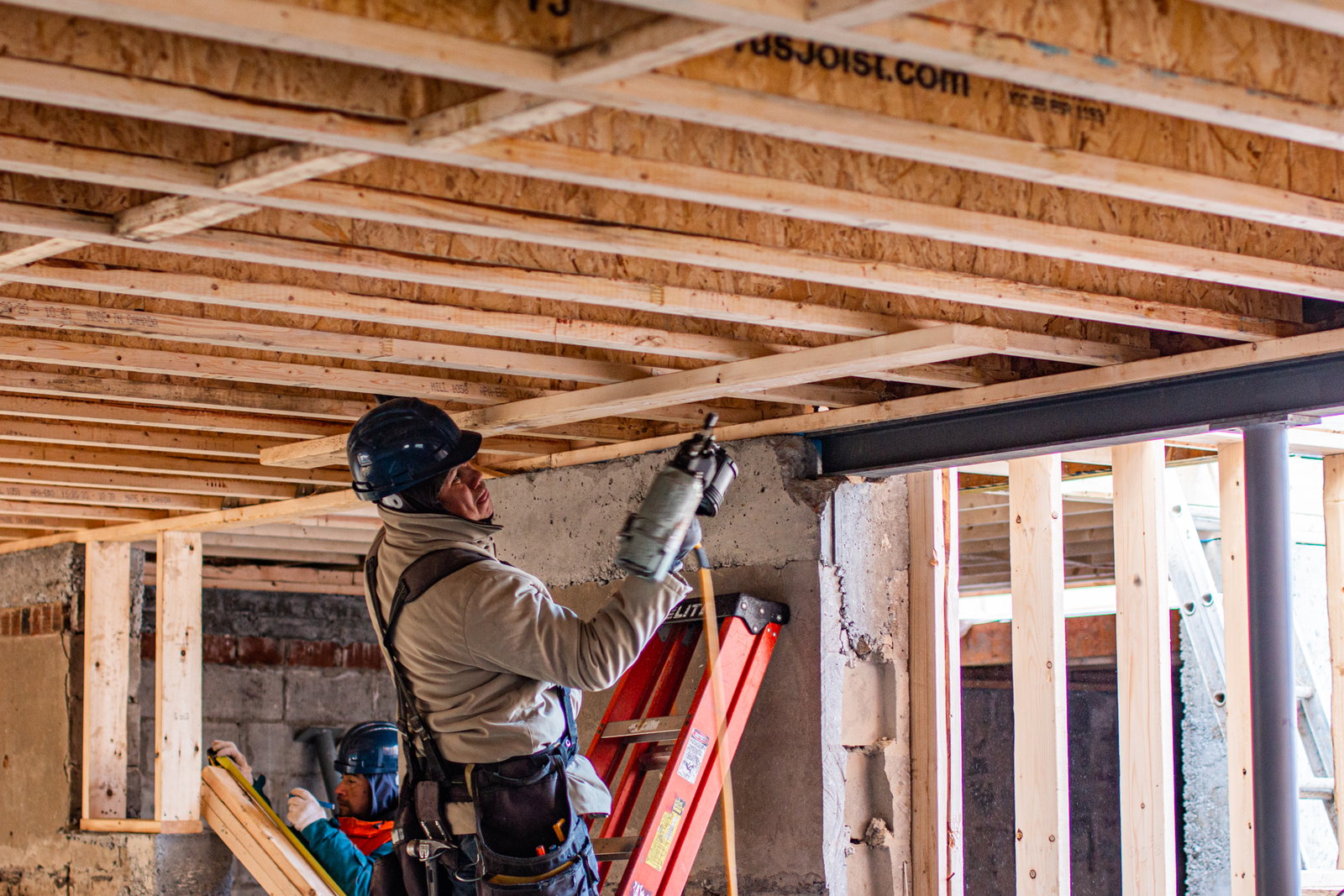 Worker constructing wooden building frame.